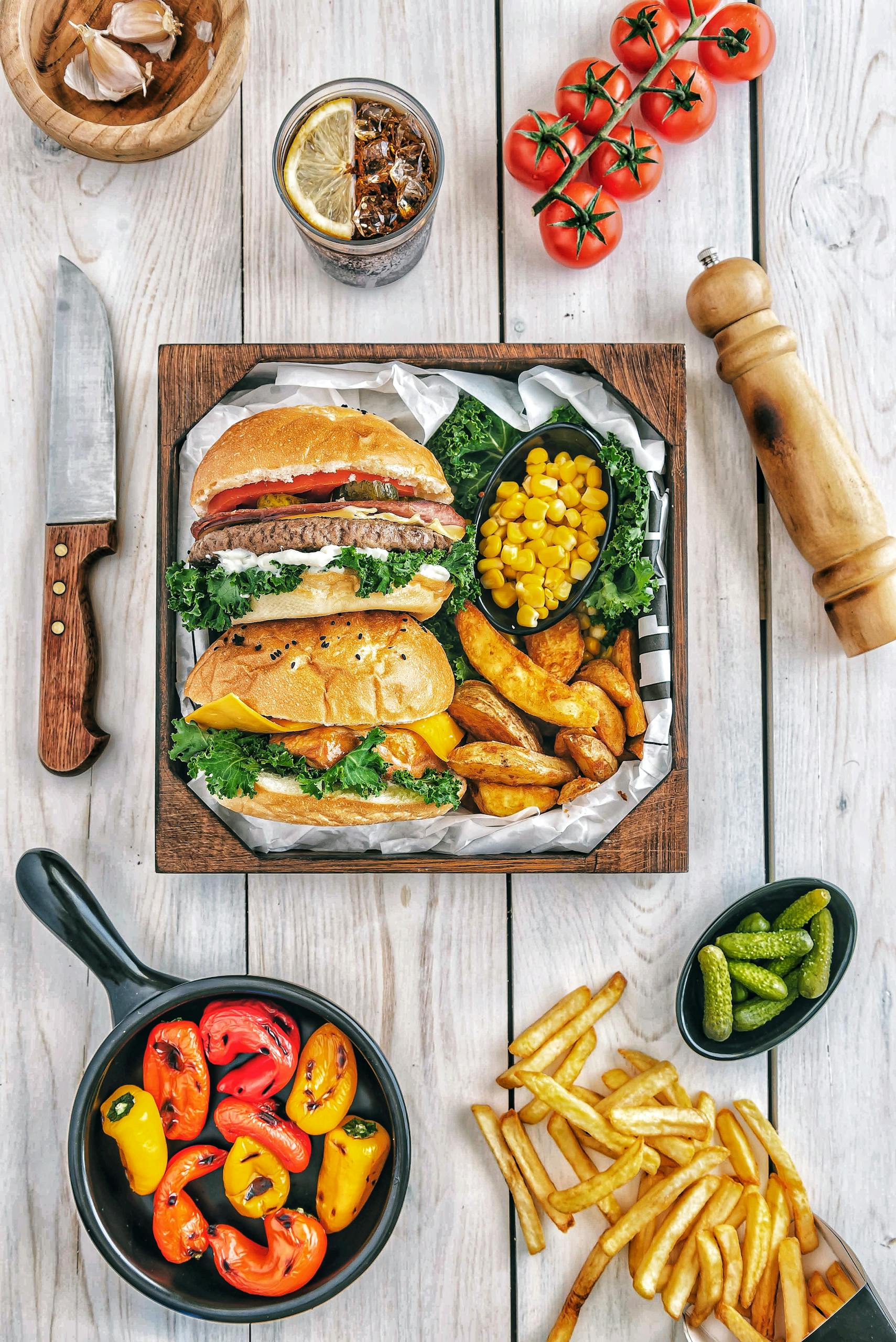 A mouth-watering gourmet burger meal with fries, peppers, and corn, perfect for a delicious dining experience.