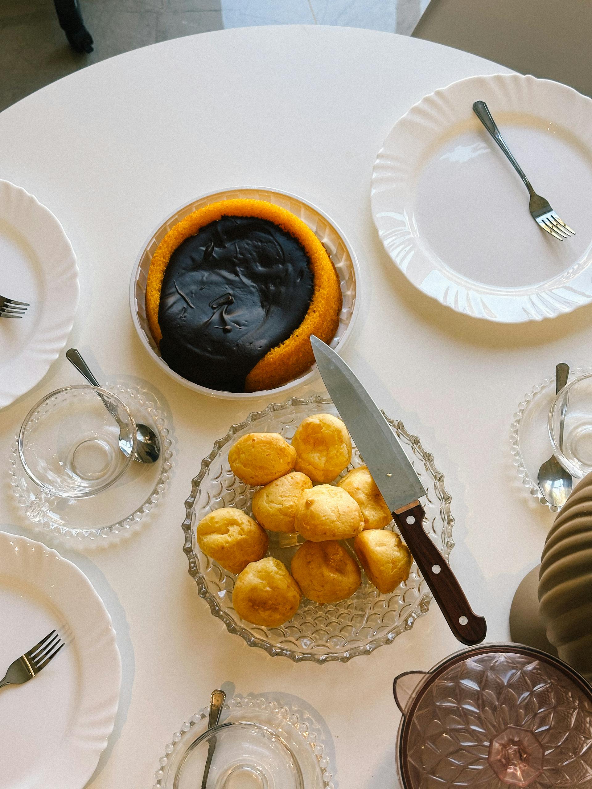 Overhead view of a Brazilian breakfast table with bolo de fubá and pão de queijo.